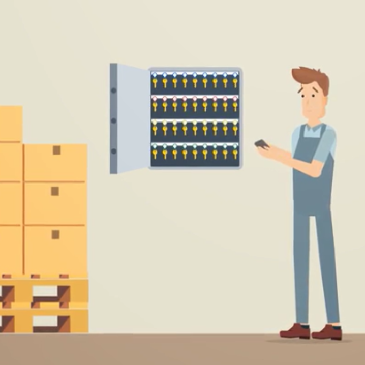 Un homme en salopette regarde une armoire à clés, près de cartons empilés.