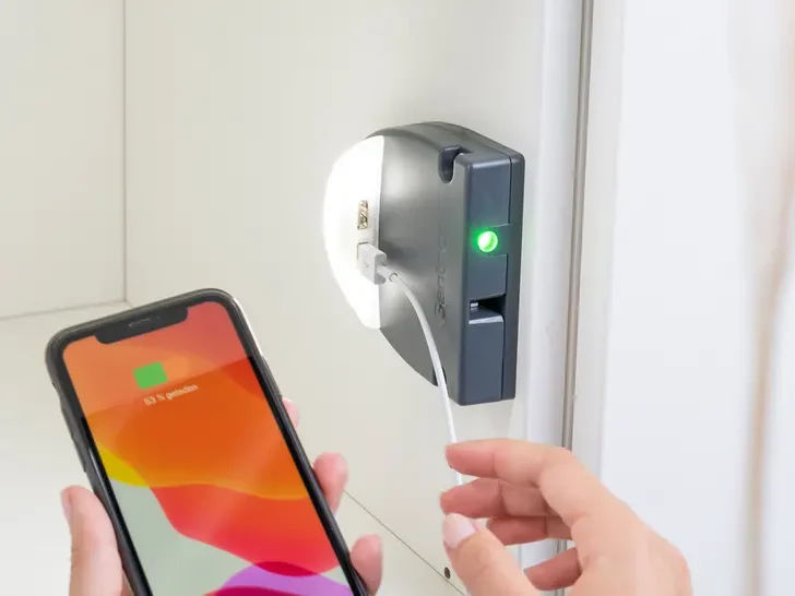 Serrue avec prise de chargeur avec un téléphone à proximité et lumière verte active.