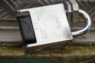 Cadenas en métal avec une partie noire, posé sur une surface métallique.