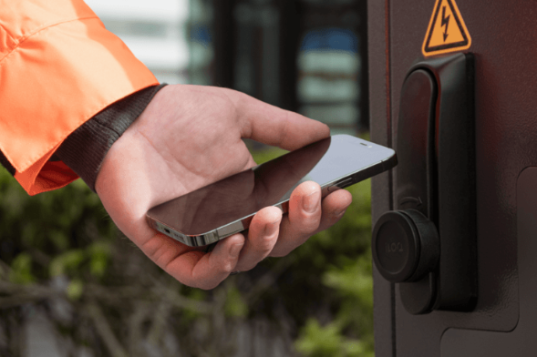Main tenant un smartphone près d'un dispositif de contrôle d'accès.