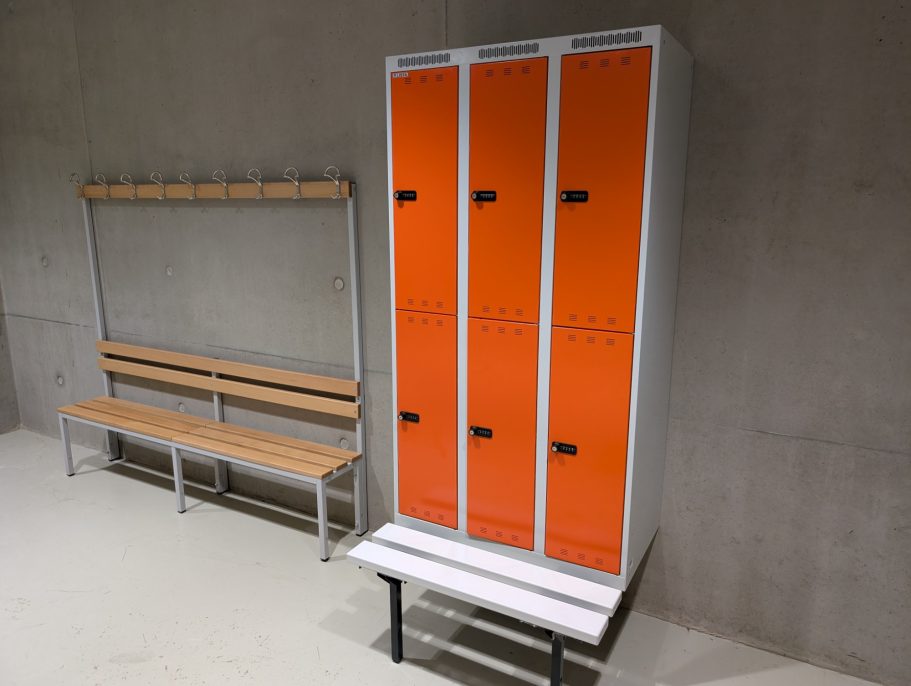Armoires-vestiaires LISTA Armoires-vestiaires orange et banc en bois dans un espace de vestiaire moderne.